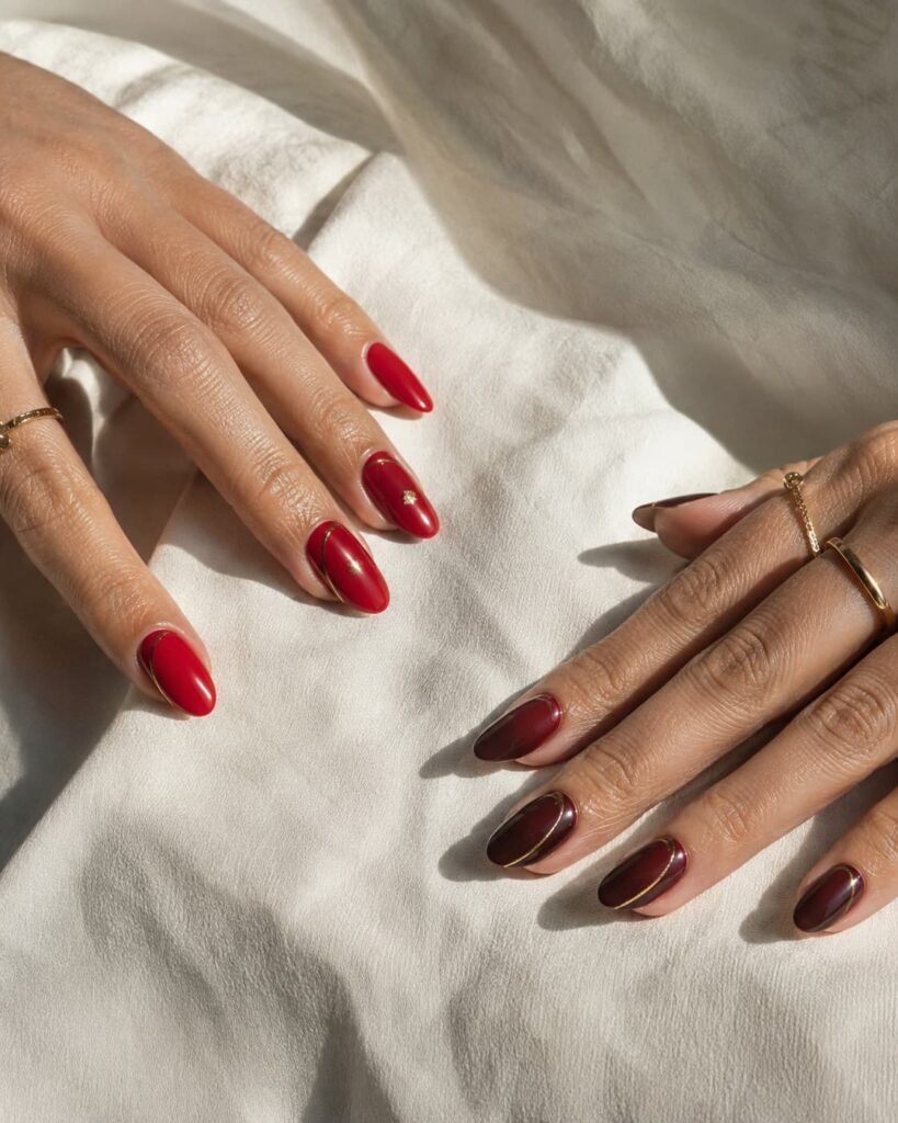 Cherry red and burgundy nails shown with fine metallic gold accents.