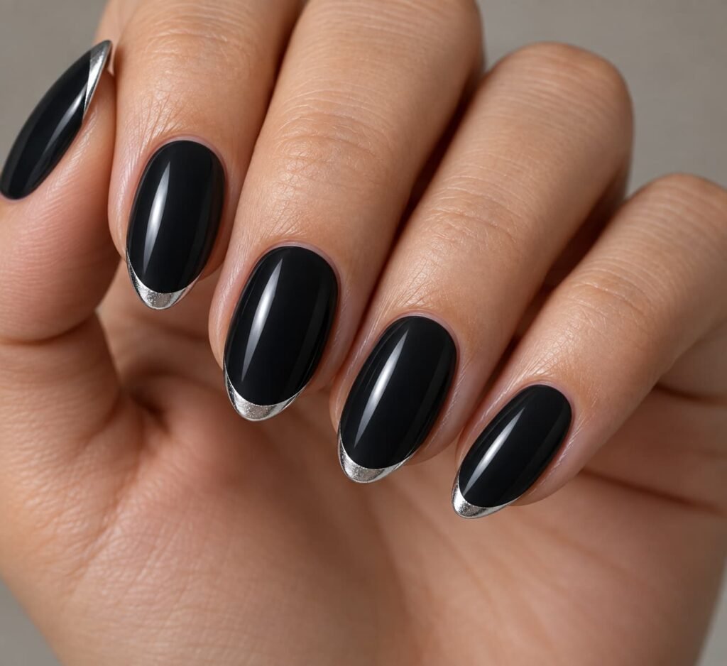 Almond-shaped nails with a dark black base and thin metallic silver French tips.