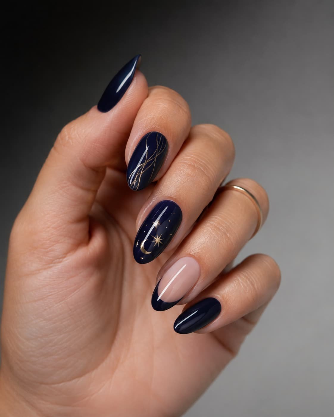 Midnight navy almond nails with gold line art, celestial details, and a sheer navy French tip.