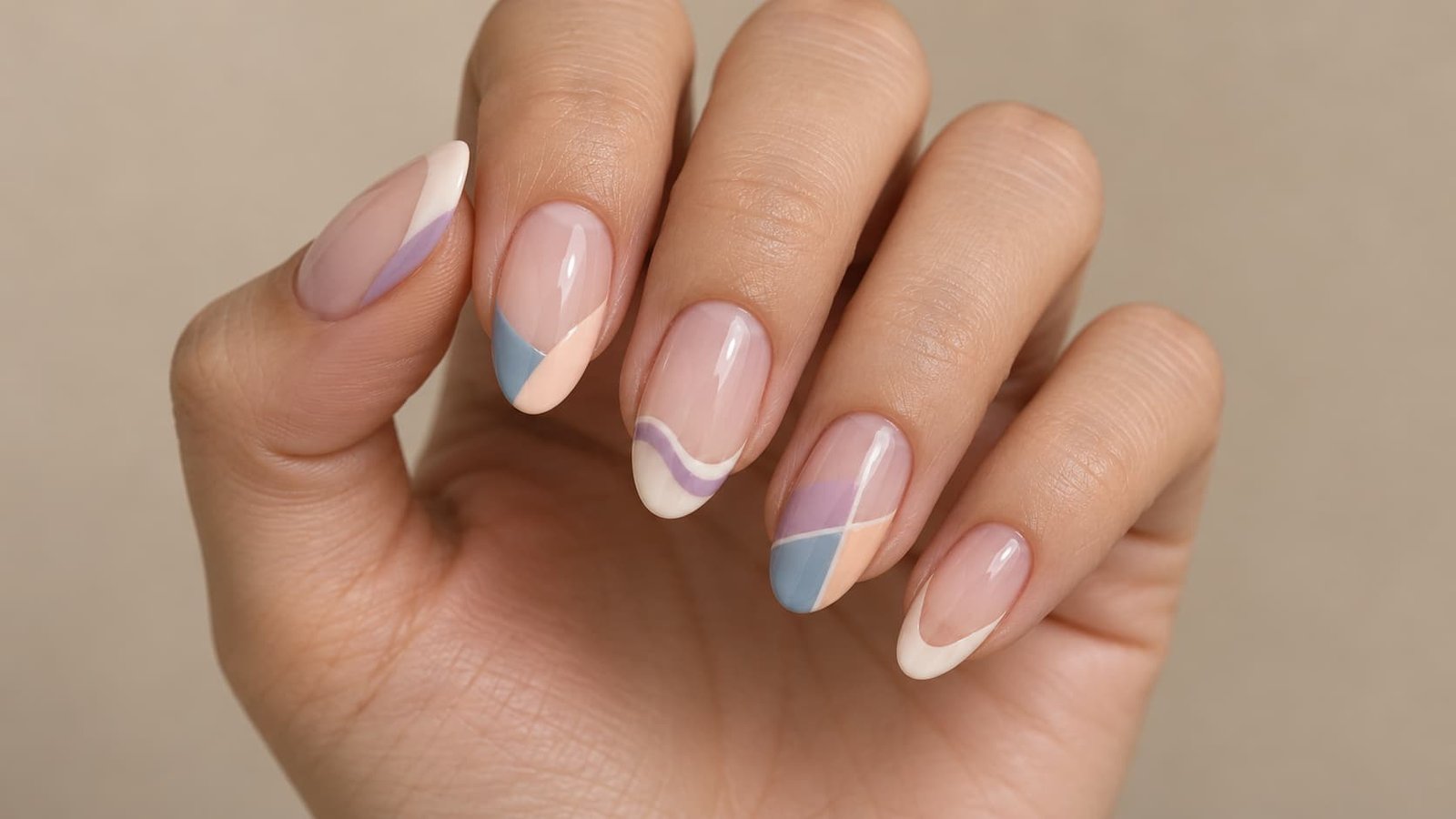 Adult hand with nude nails featuring curved, wavy, geometric, and negative-space French tips.