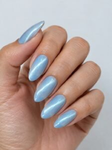 Light blue cat eye manicure on almond-shaped nails with a reflective magnetic stripe.